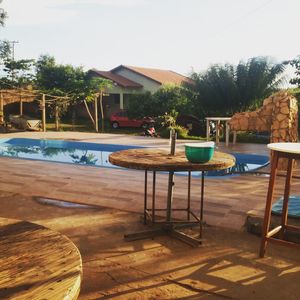 Chairs and table by swimming pool against sky