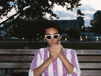 Portrait of man wearing sunglasses while sitting on bench