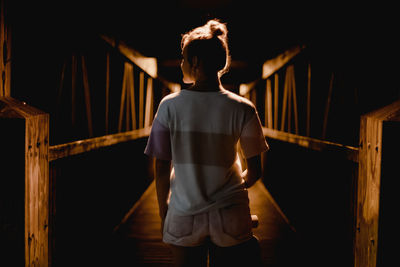Rear view of woman standing on footbridge at night