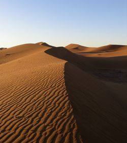 Sand dune in desert against clear sky