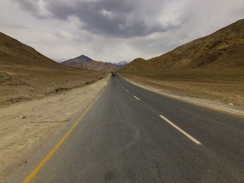 Road leading towards mountains against sky