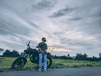 Man sitting on field against sky