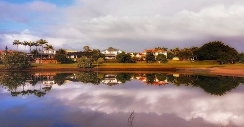 Reflection of houses and trees in lake against sky