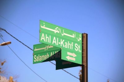 Low angle view of road sign against blue sky