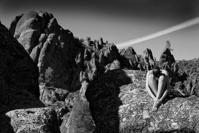 Man standing on rock against sky