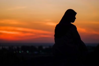 Silhouette woman against orange sky during sunset