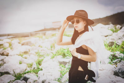 Woman wearing hat standing against plants