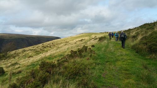 Rear view of people walking on land against sky