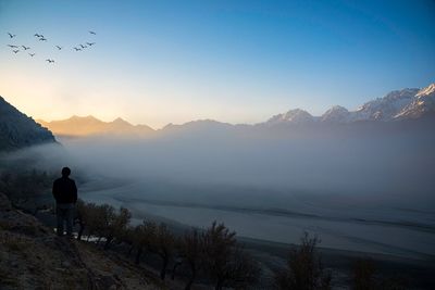 Rear view of man standing on mountain against sky