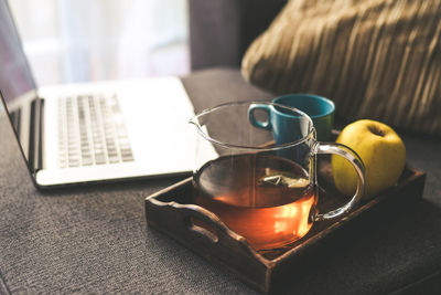 Still life of a natural breakfast at home beside a laptop on the sofa. tea, coffee on a wooden tray 