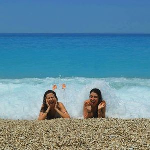 Friends enjoying at beach against blue sky on sunny day