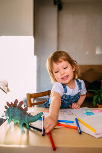 Cute girl holding color pencil at home