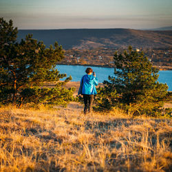 Rear view of man standing on land against sky