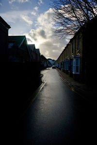 Empty road amidst buildings against sky