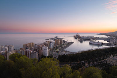 High angle view of buildings by sea against sky during sunset