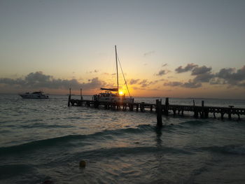 Silhouette sailboat in sea against sky during sunset