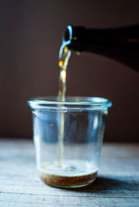 Cropped image of beer pouring in glass on table