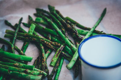 High angle view of roasted asparagus by cup on table