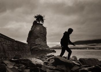 Man standing on rock against sky