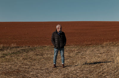 Portrait of adult man in winter cloth on field against blue sky. shot in castilla y leon, spain