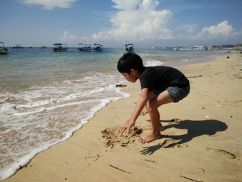 Boy playing with sand at shore