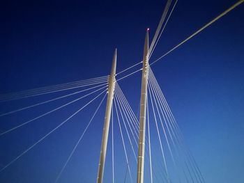 Low angle view of suspension bridge against blue sky