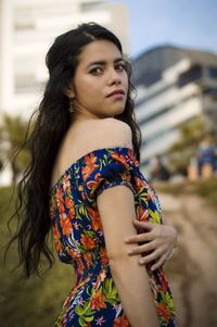 Portrait of young woman standing against wall