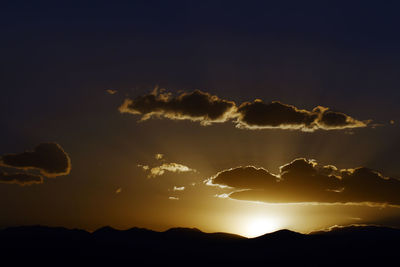 Low angle view of silhouette mountains against dramatic sky