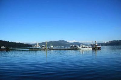 Boats in calm sea against clear sky