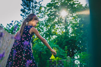 Side view of girl standing against trees in forest