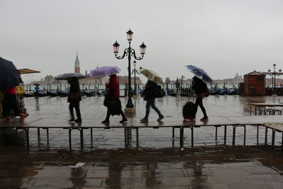 People on lake against sky in city