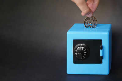 Close-up of hand holding coin against blue background