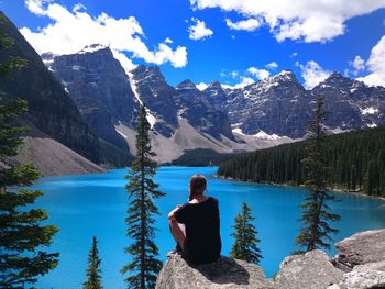 Rear view of woman looking at lake against mountains