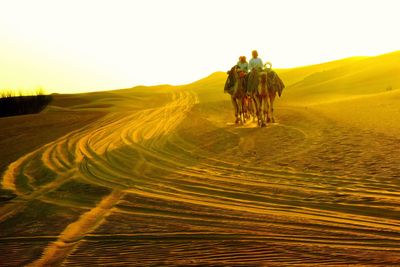 People riding motorcycle on land against sky