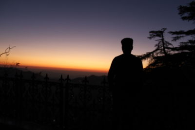 Rear view of silhouette man standing against sky during sunset