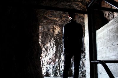 Rear view of person standing in cave