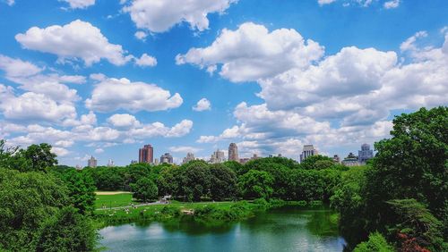 Panoramic view of trees and buildings against cloudy sky
