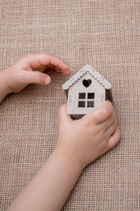 Cropped hand of kid holding model home on burlap