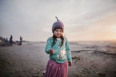 Girl standing on beach against sky during sunset