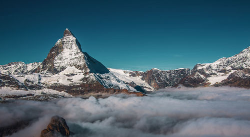 Scenic view of snowcapped mountains against clear blue sky