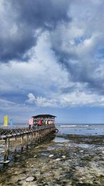 Pier over sea against cloudy sky