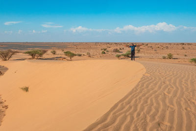 A man standing on a beautiful sand dune at north horr sand dunes in marsabit county, kenya