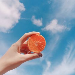 Midsection of person holding apple against sky