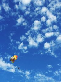 Low angle view of people paragliding against sky