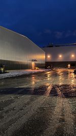 Illuminated city street against sky at night