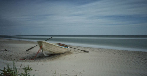 Fishing boat on beach against sky