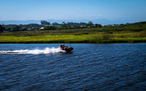 People on boat in river against sky