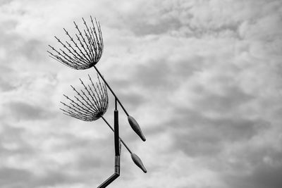 Low angle view of giant dandelion seed against cloudy sky