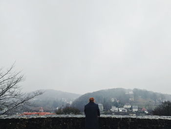 Rear view of man looking at mountain against sky