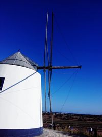 Low angle view of traditional windmill against clear blue sky